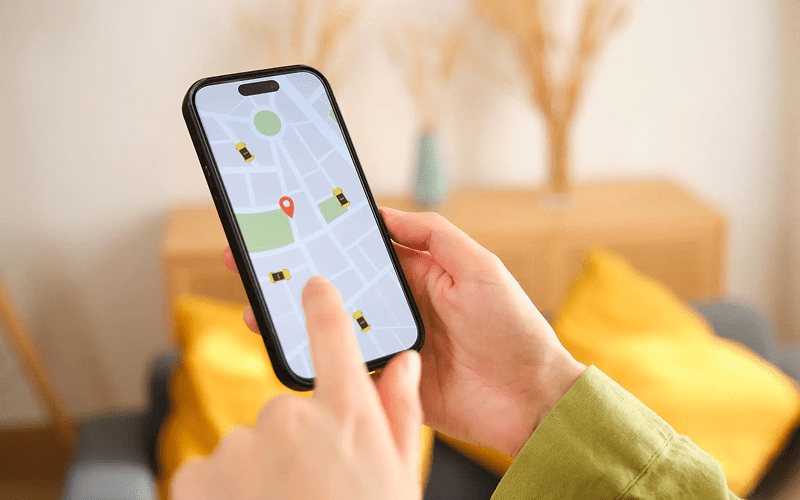 A person holds a smartphone displaying a map app with a red location pin