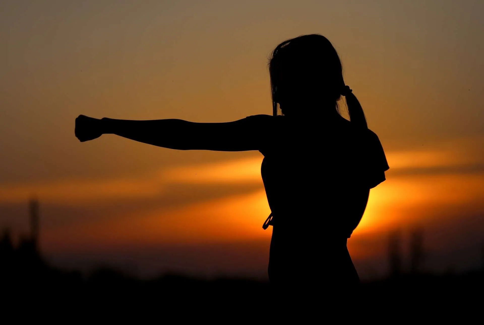 Silhouette of person punching at sunset.